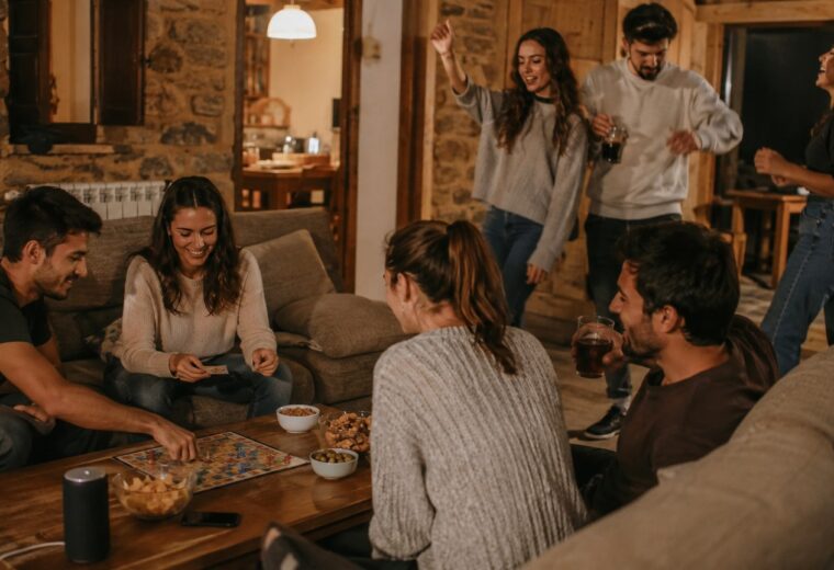 Seis amigos charlan, juegan y bailan en el salón de una casa rural